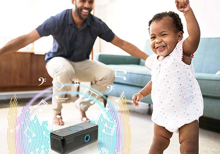Father and Baby in living dancing to music being played from AAXA's Portable Bluetooth Speaker Projector.